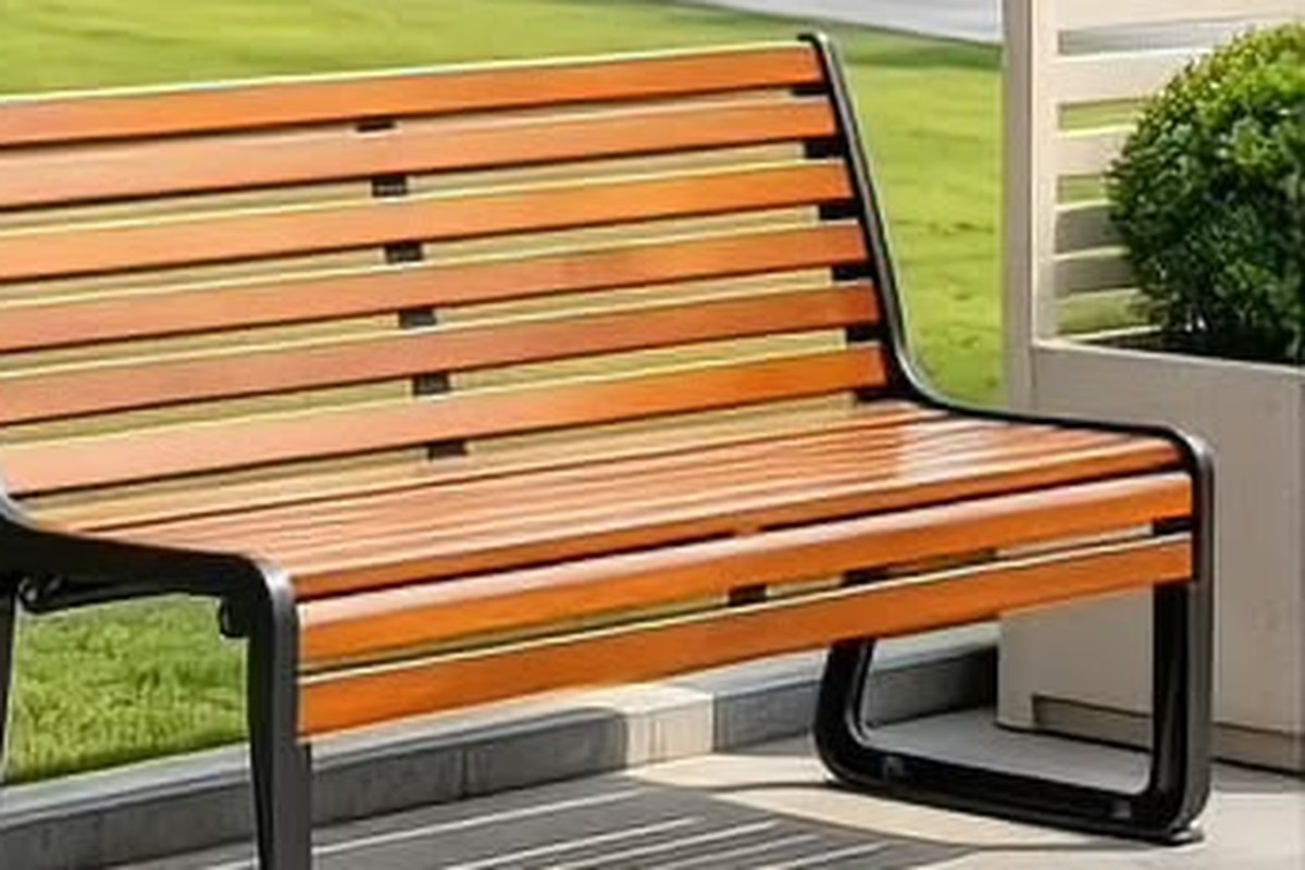 Hardwood slat park bench with black steel frame in a green public park after maintenance